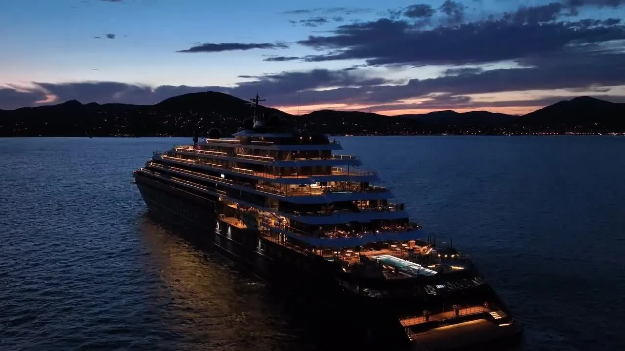 A Ritz-Carlton Yacht Collection yacht lit up at anchor at dusk