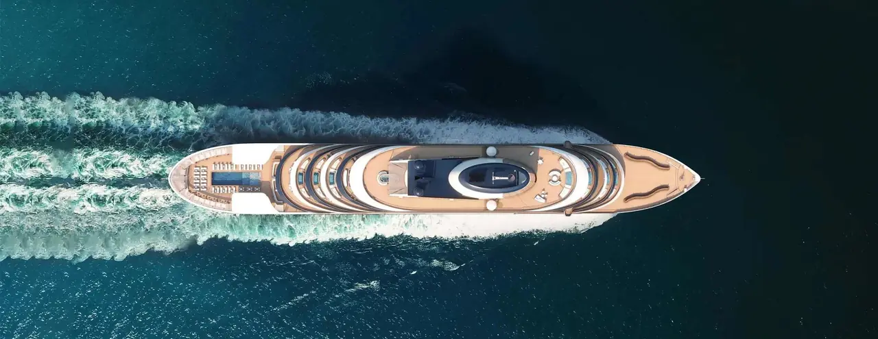 Aerial view of a Four Seasons yacht cutting through deep blue water