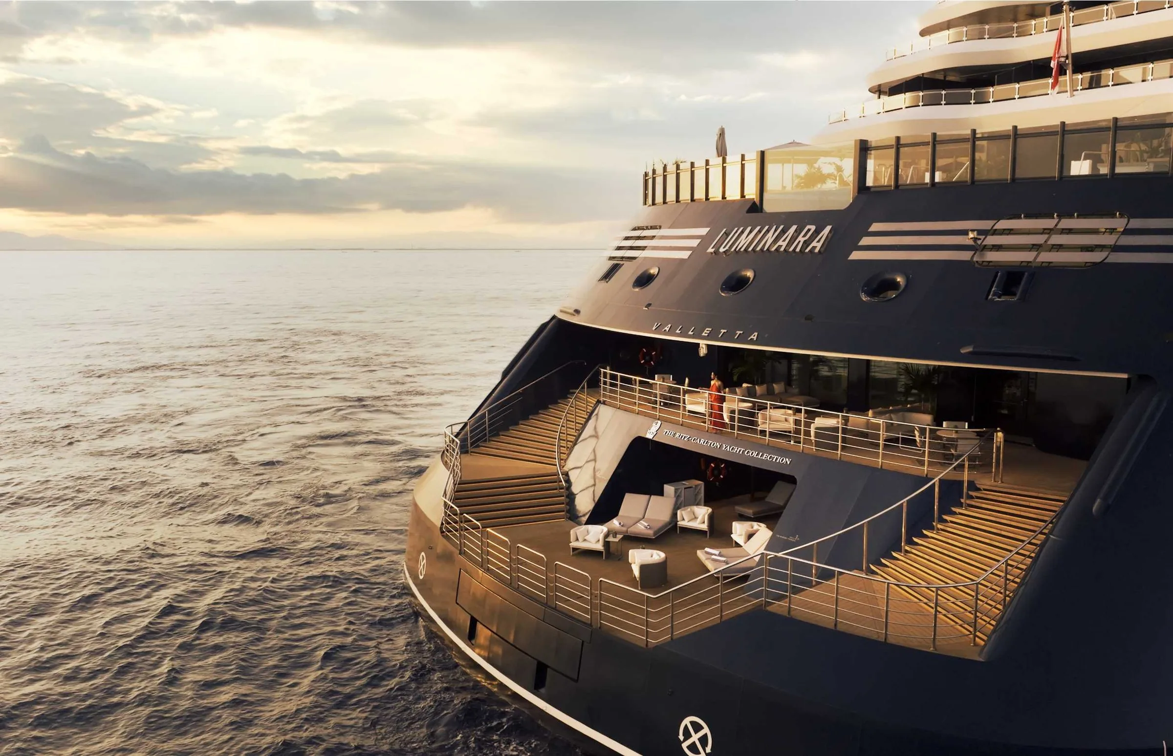The stern of Luminara at sunset, with its open-air marina deck and lounge